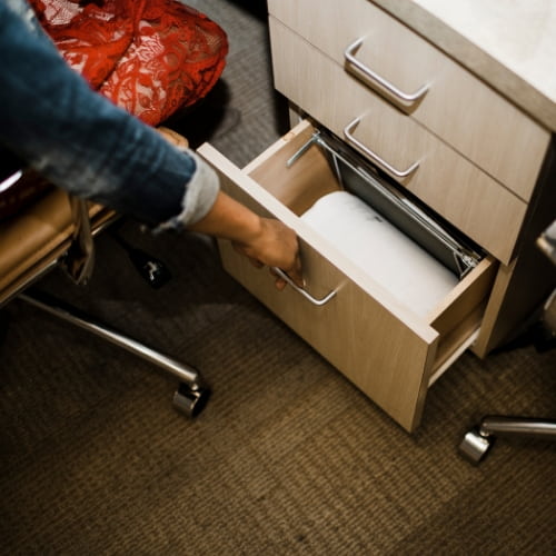 Our front desk coordinator reaching into a filing cabinet drawer as she helps you understand your orthodontic insurance benefits.